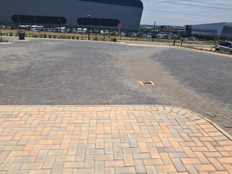 A paved industrial parking and driveway area featuring durable block paving, perimeter fencing, and integrated drainage infrastructure.