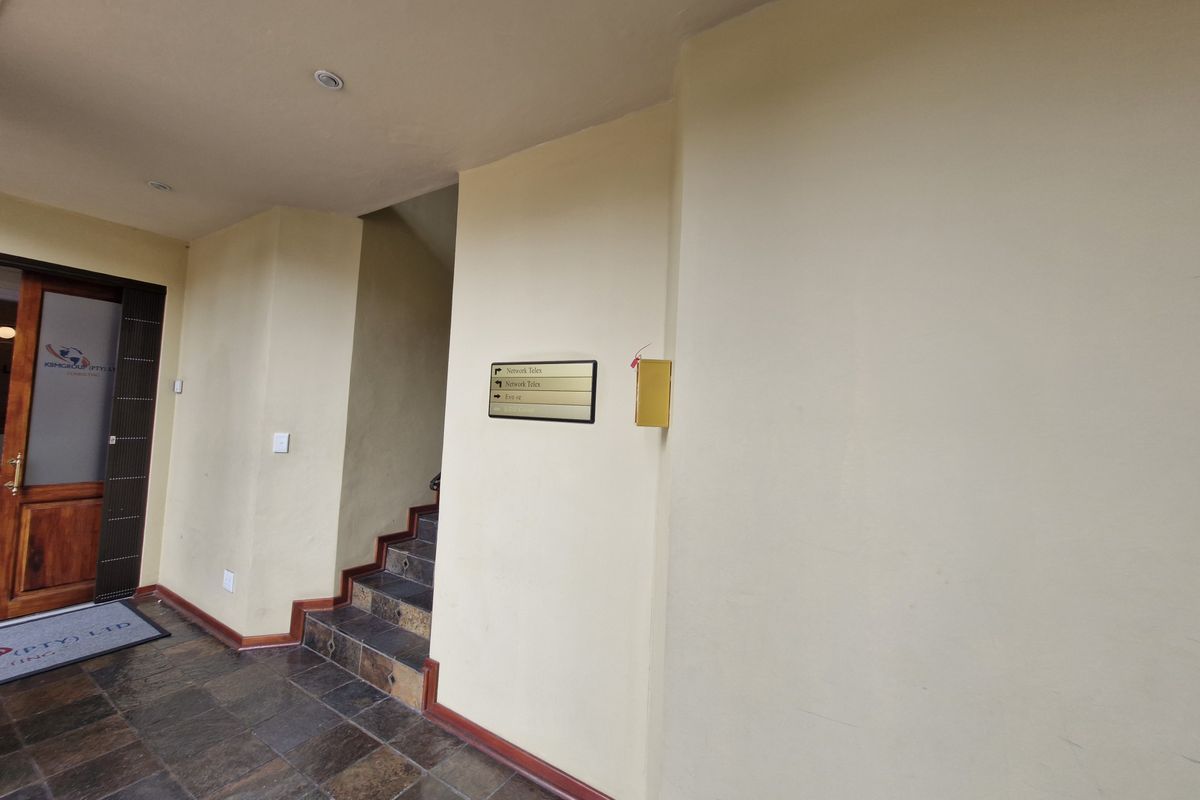 Commercial building entrance foyer featuring tiled flooring, a staircase leading to upper levels, and wall-mounted directory signage.