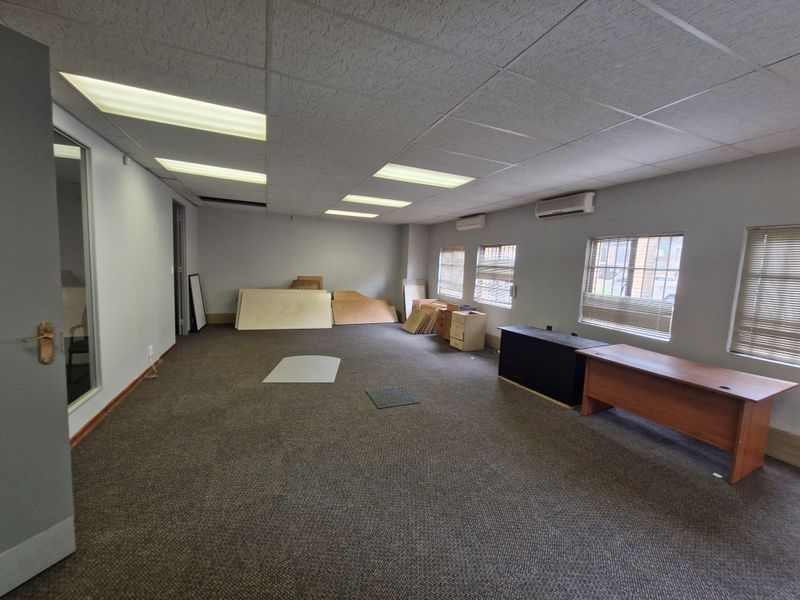 Spacious commercial office area featuring suspended ceilings, recessed lighting, split-system air conditioning, and carpeted flooring, suitable for a professional workspace.