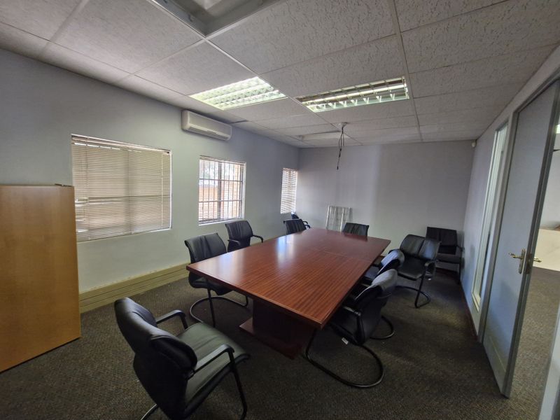 A functional office space featuring a suspended ceiling, split-system air conditioning, and carpeted flooring, suitable for a professional meeting or workspace environment.
