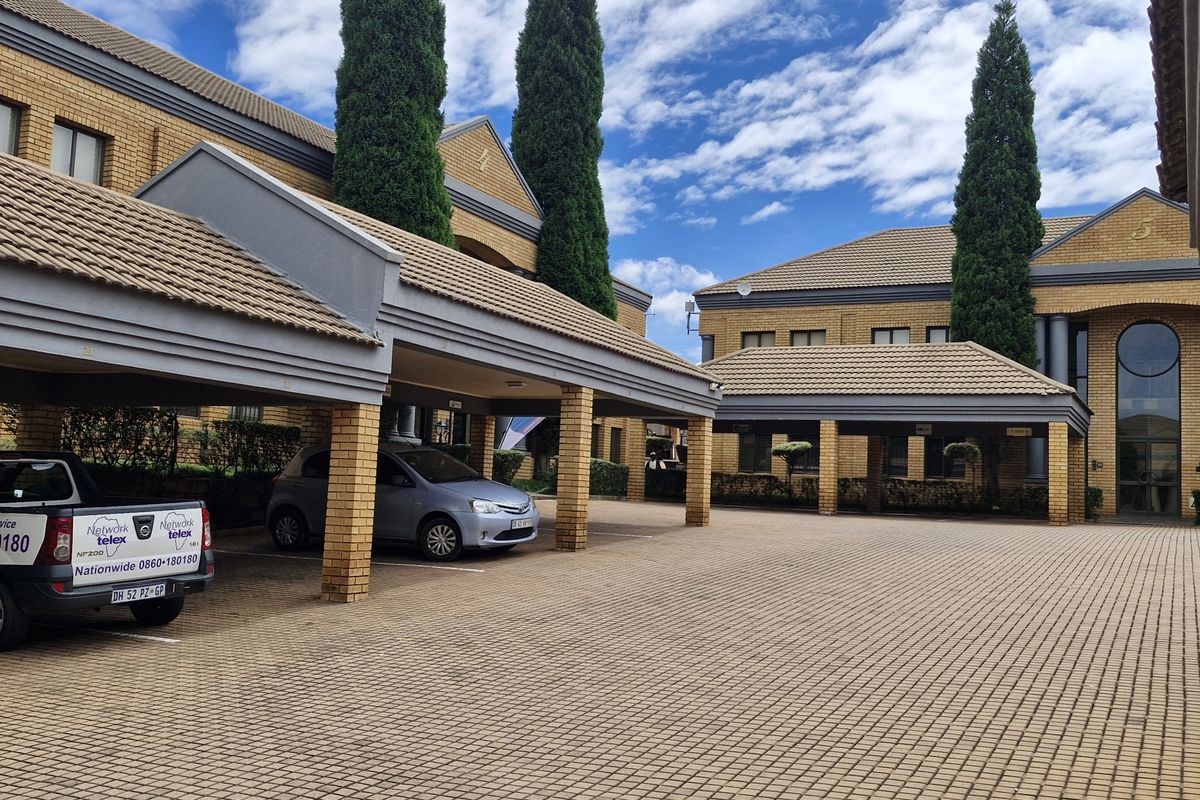 Commercial office complex exterior featuring brick paved parking area with covered bays and well-maintained brick building facades.