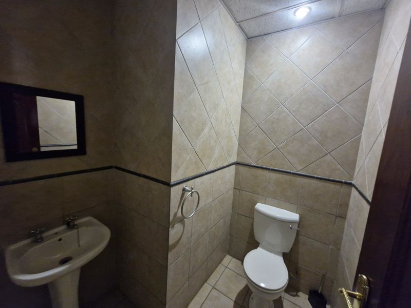A functional bathroom featuring tiled walls and flooring, equipped with a pedestal basin and a standard toilet.
