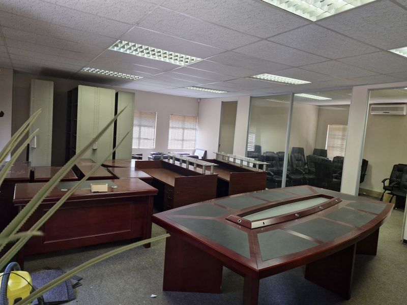 Spacious commercial office area featuring glass partitions, suspended ceilings with recessed lighting, built-in storage cabinets, and an integrated air conditioning unit.