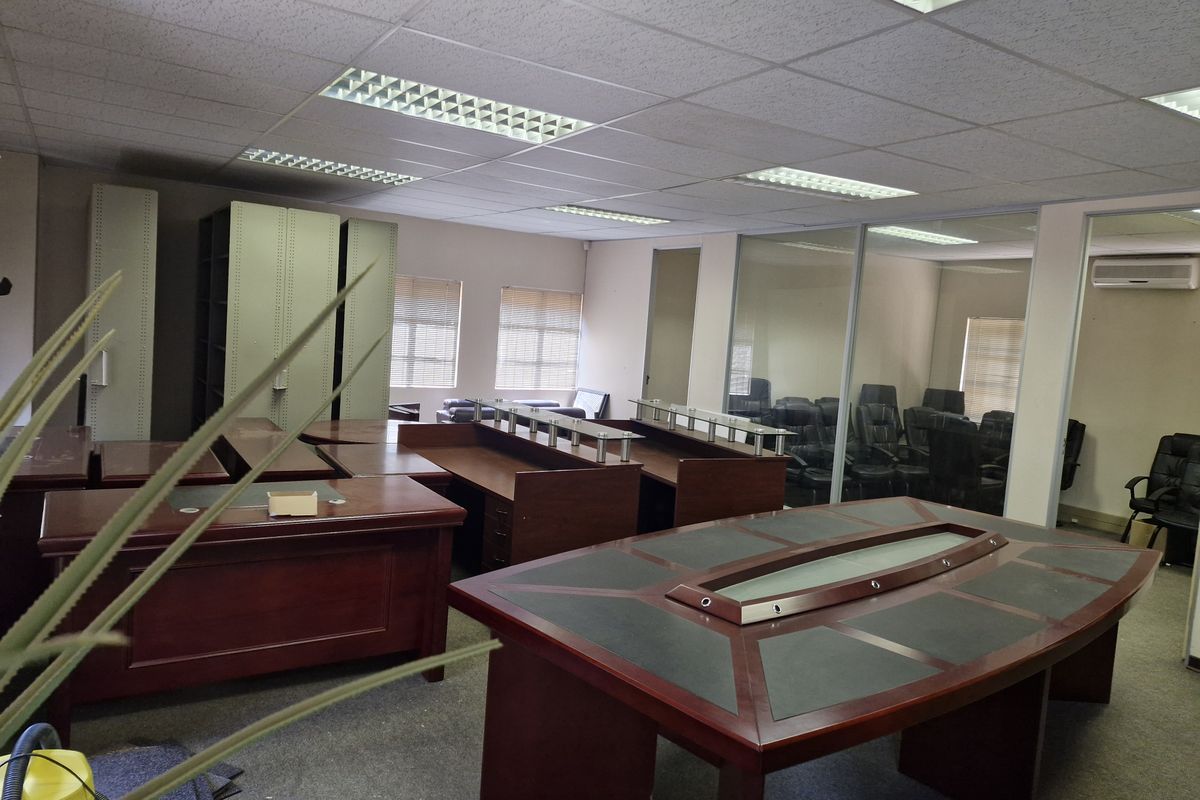 Spacious commercial office area featuring glass partitions, suspended ceilings with recessed lighting, built-in storage cabinets, and an integrated air conditioning unit.