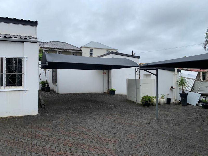 Rear exterior area featuring a paved driveway with shade cloth carports and secure boundary walls.