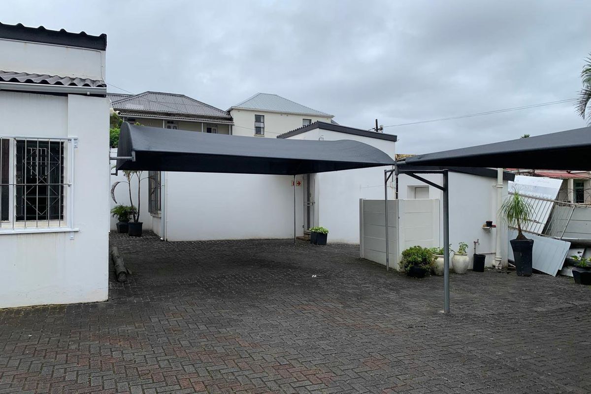 Rear exterior area featuring a paved driveway with shade cloth carports and secure boundary walls.