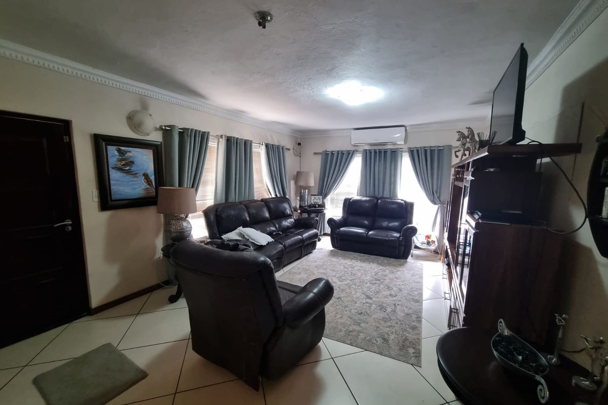 A comfortable living room featuring tiled flooring, crown molding, and a wall-mounted split-system air conditioner for climate control.