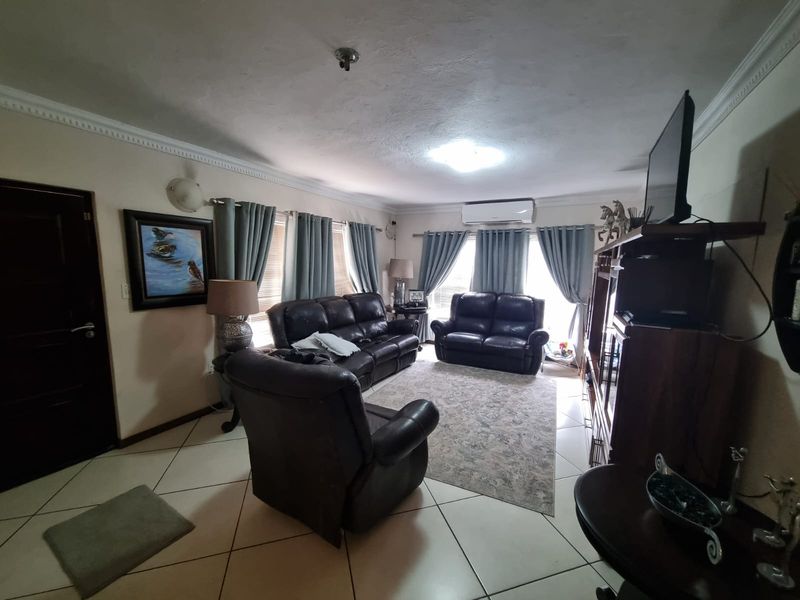 A comfortable living room featuring tiled flooring, crown molding, and a wall-mounted split-system air conditioner for climate control.