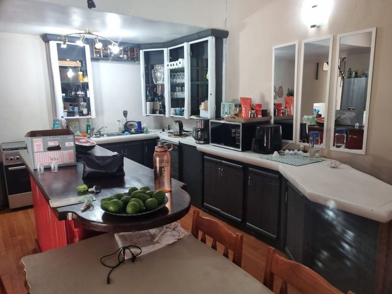 A functional kitchen featuring dark built-in cabinetry, a central island, hardwood flooring, and ample counter space for food preparation.