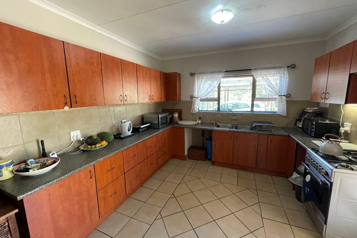 A functional kitchen featuring laminate cabinetry, granite countertops, a double basin sink, and tiled flooring, offering a practical layout for daily meal preparation.