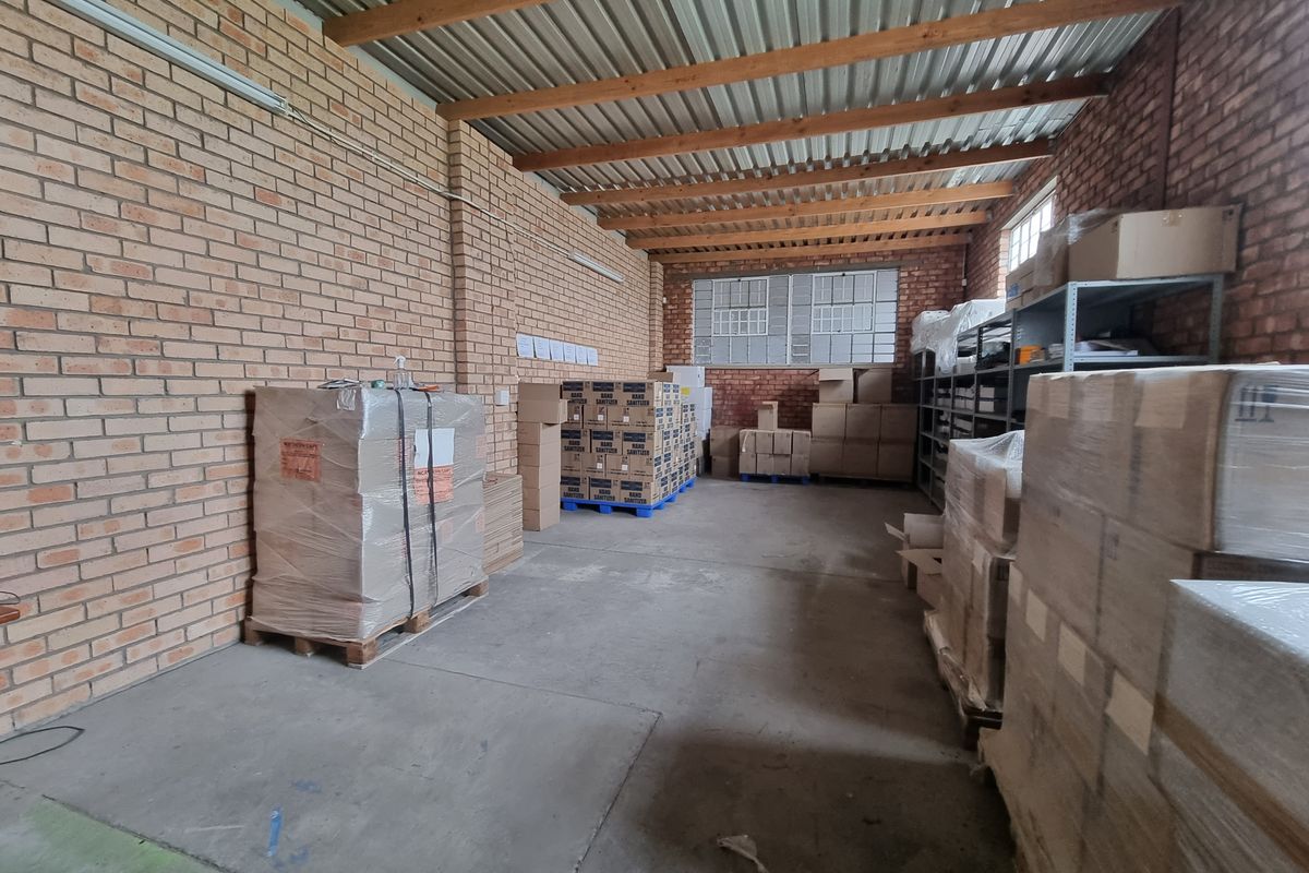 A functional utility or storage space featuring exposed brick walls, timber rafters, and durable concrete flooring, suitable for industrial or commercial use.