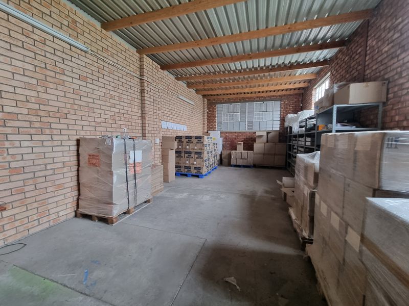 A functional utility or storage space featuring exposed brick walls, timber rafters, and durable concrete flooring, suitable for industrial or commercial use.
