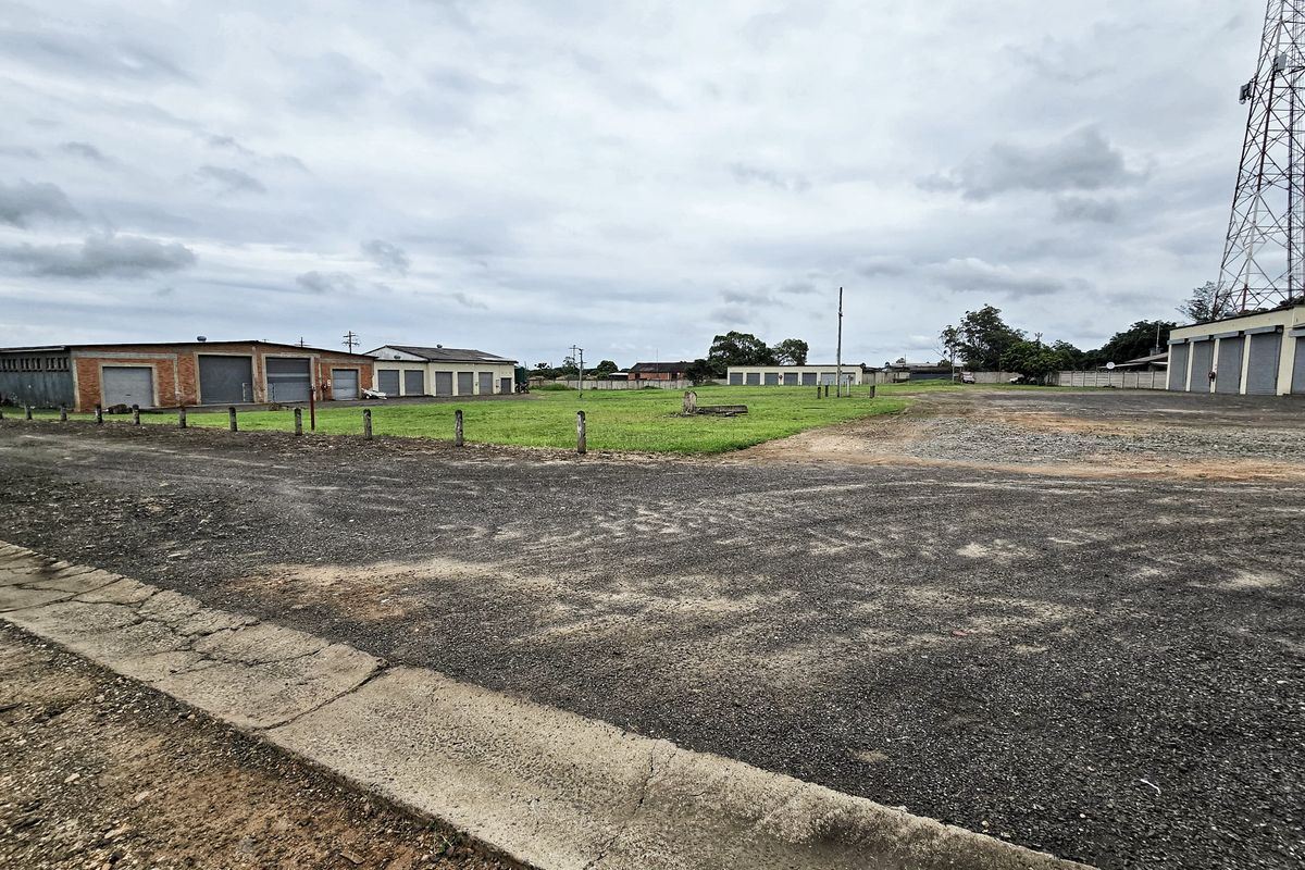 Expansive industrial property featuring multiple warehouse units with roller shutter doors, a large gravel yard, and a telecommunications tower on site.