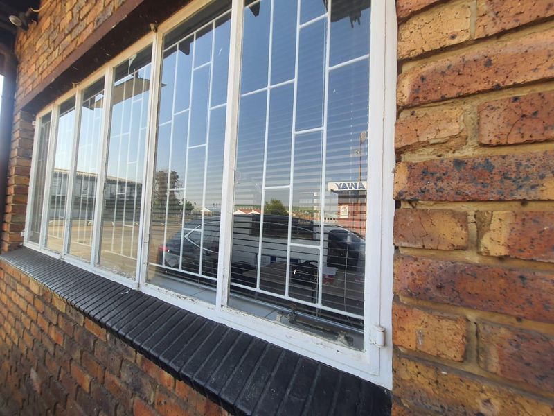 Close-up view of a face brick exterior wall featuring steel-framed windows with integrated security burglar bars.