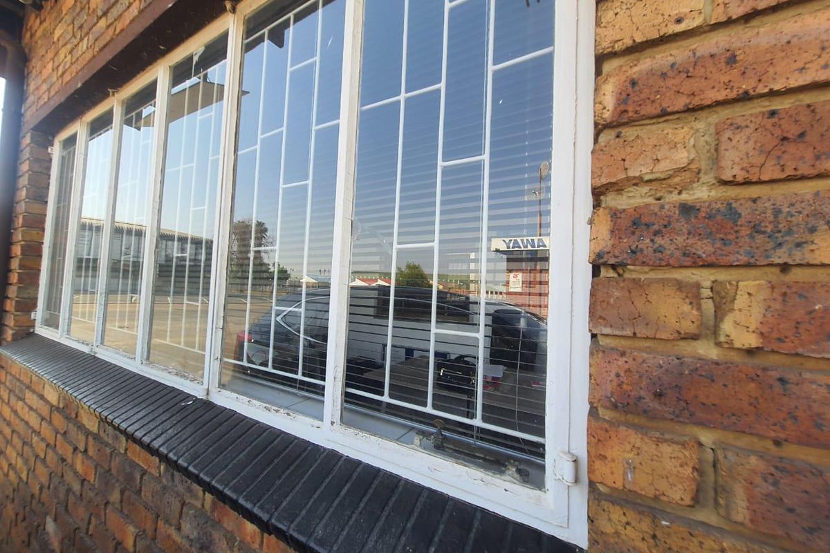 Close-up view of a face brick exterior wall featuring steel-framed windows with integrated security burglar bars.