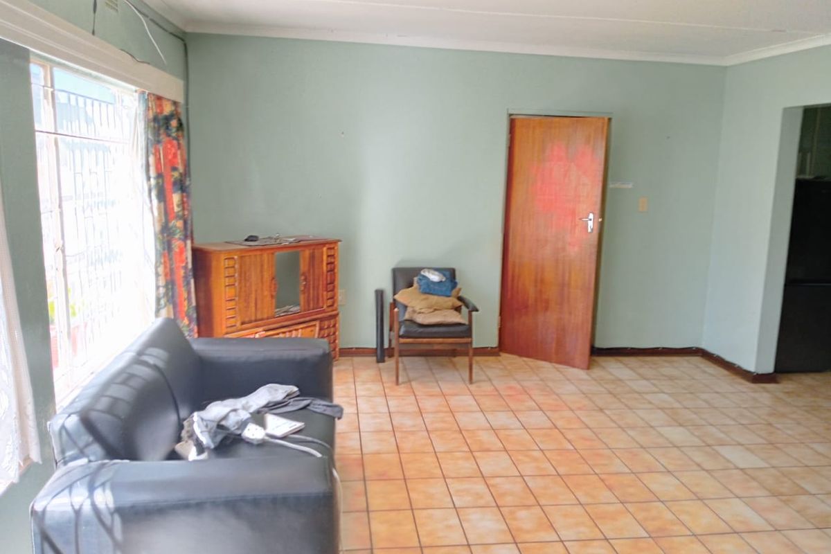 A living area featuring tiled flooring and a timber door, offering a functional space with potential for cosmetic updates and modernization.