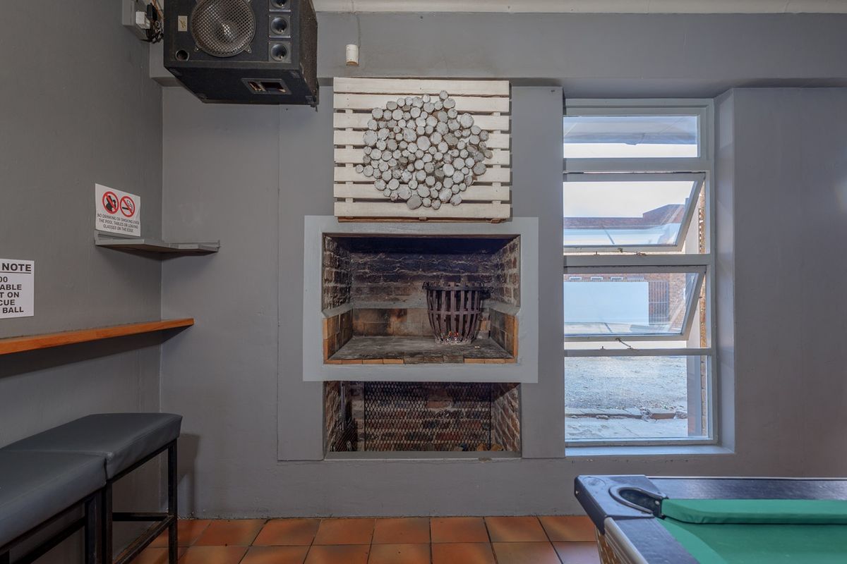 Indoor entertainment area featuring a built-in brick fireplace, tiled flooring, and large windows providing natural light.