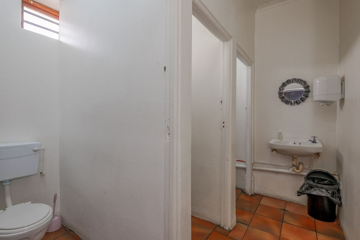 A functional commercial restroom facility featuring tiled flooring, a wall-mounted basin, and a separate toilet cubicle.