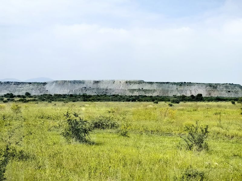 A scenic view of the expansive farm landscape featuring open grasslands and a prominent rocky ridge in the distance.