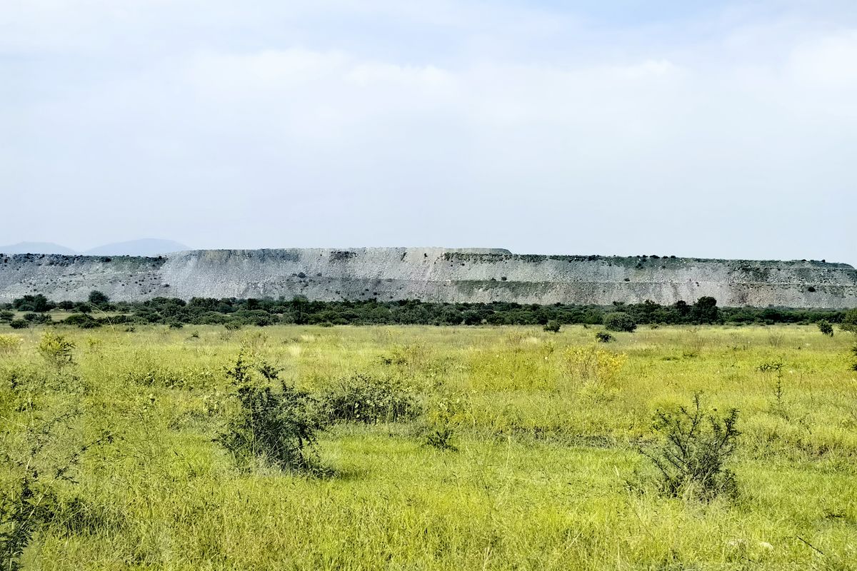 A scenic view of the expansive farm landscape featuring open grasslands and a prominent rocky ridge in the distance.