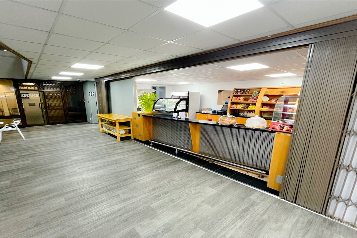 A functional office canteen or service area featuring a built-in service counter, suspended ceiling, and durable laminate flooring.