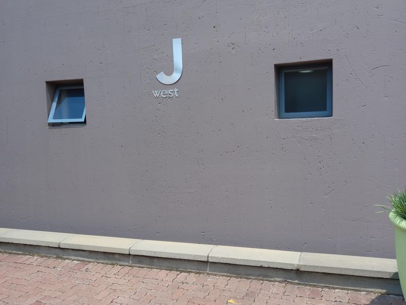 Exterior view of the J West office building facade featuring a textured wall finish, paved driveway, and small casement windows.