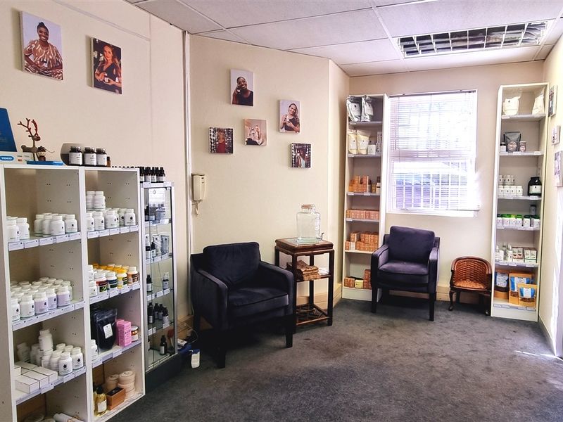 A functional office space featuring carpeted flooring, suspended ceiling with recessed lighting, and built-in shelving units for storage.