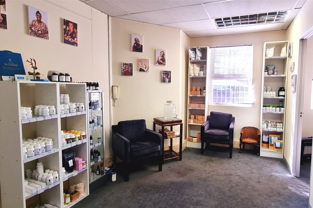 A functional office space featuring carpeted flooring, suspended ceiling with recessed lighting, and built-in shelving units for storage.