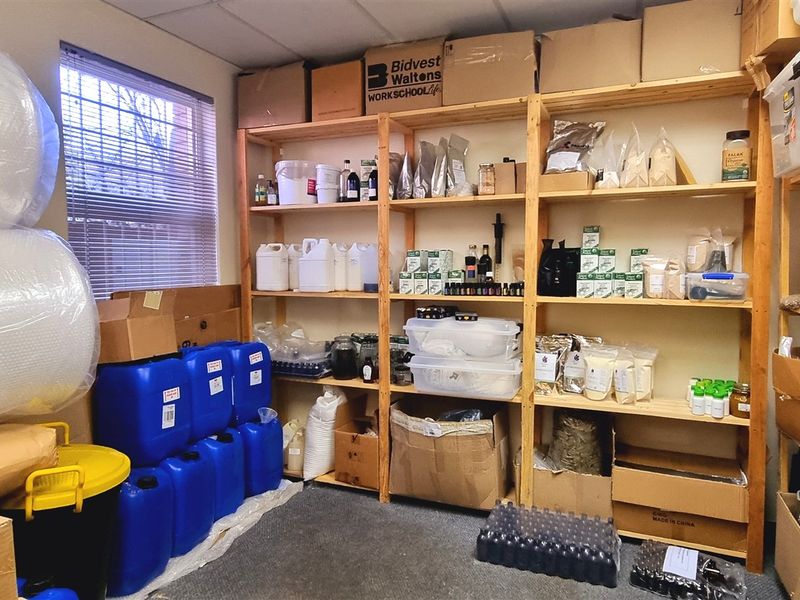A functional utility or storage room featuring built-in wooden shelving units and a suspended ceiling, currently utilized for inventory storage.