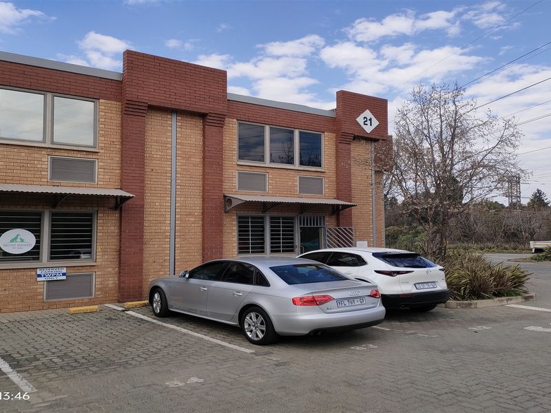 Front exterior view of an industrial unit featuring a brick facade, security gates, and dedicated paved parking spaces.