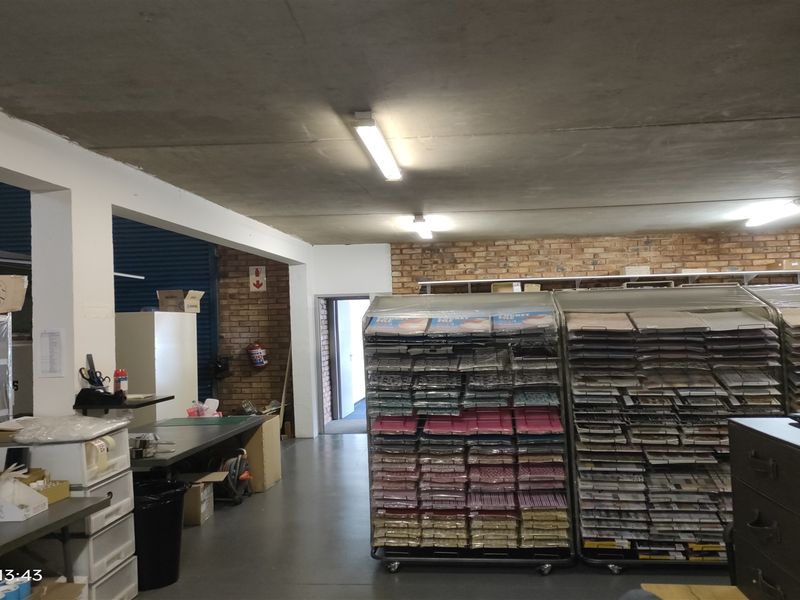 Industrial utility or storage space featuring exposed brick walls, concrete ceiling, and functional overhead fluorescent lighting.