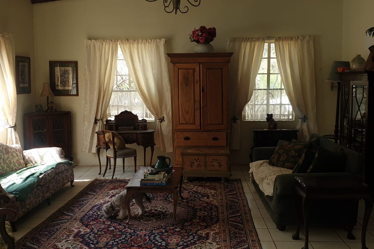 A traditional living room featuring tiled flooring, large multi-pane windows allowing natural light, and a classic wrought iron chandelier.