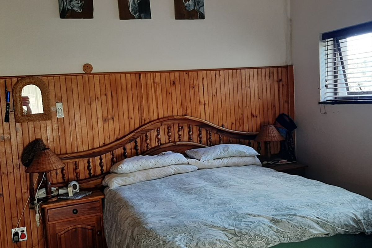 A bedroom featuring timber wall paneling, a built-in wardrobe, and venetian blinds, offering a rustic aesthetic with potential for modern updates.