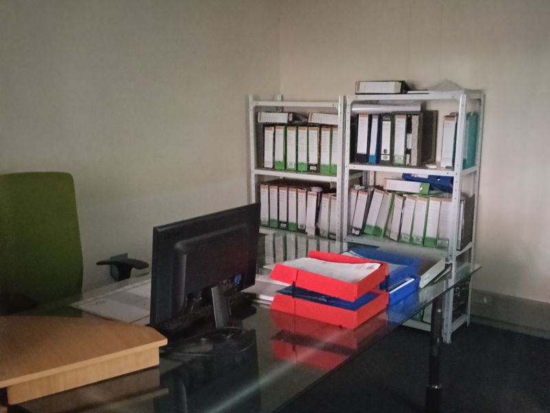 A functional office space featuring carpeted flooring, coving, and a wall-mounted split-system air conditioning unit.