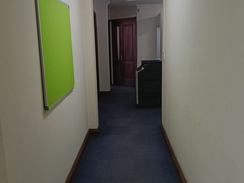 A functional office hallway featuring carpeted flooring, crown molding, and access to private office spaces.
