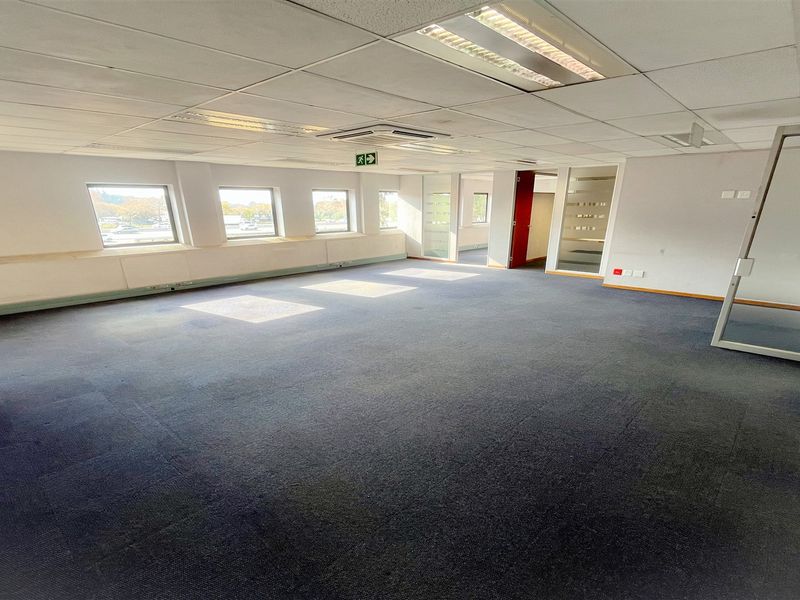 Spacious open-plan office area featuring suspended ceilings, recessed lighting, and glass partition doors, providing a versatile workspace environment.
