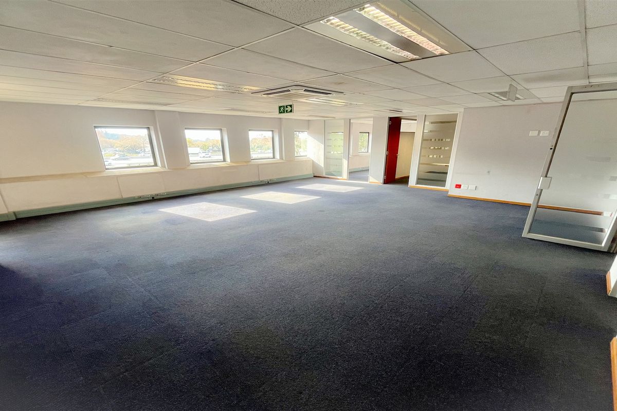 Spacious open-plan office area featuring suspended ceilings, recessed lighting, and glass partition doors, providing a versatile workspace environment.