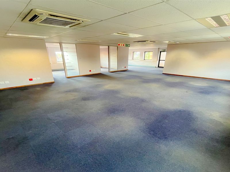 Spacious open-plan office area featuring suspended ceilings, recessed lighting, ducted air conditioning, and glass partition walls, providing a flexible workspace layout.