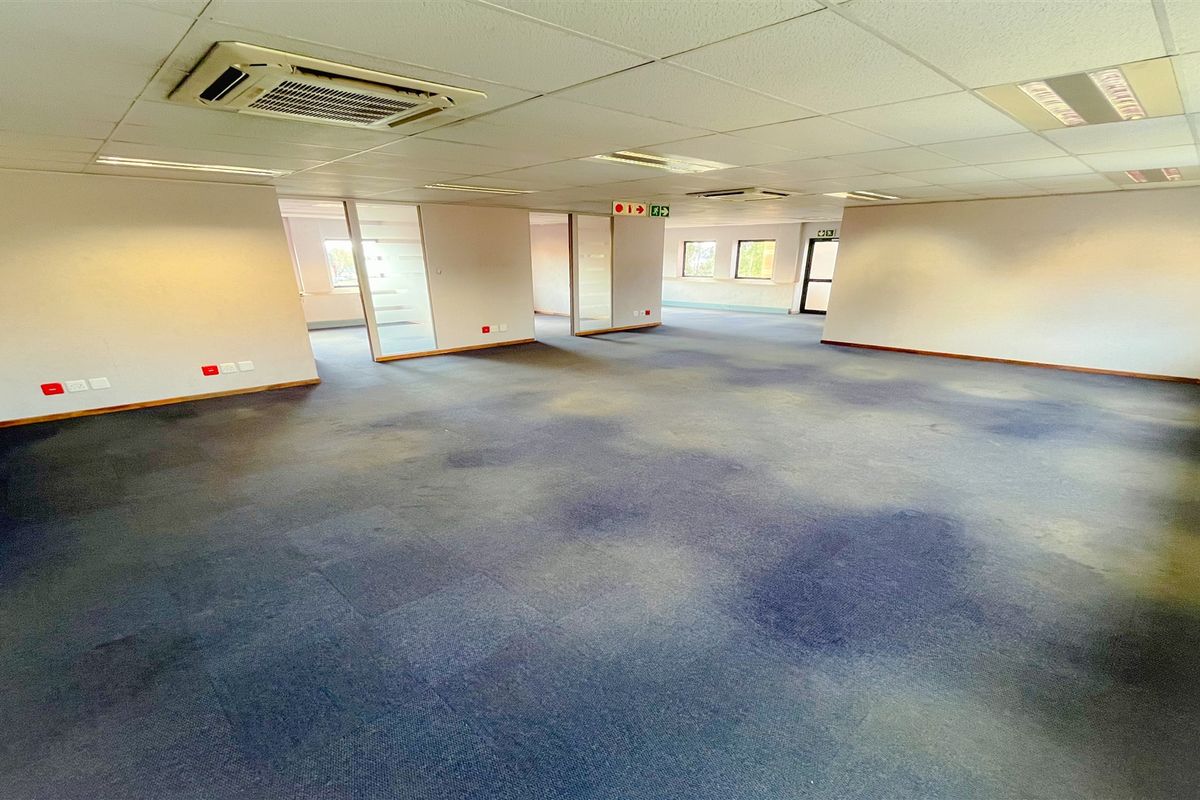 Spacious open-plan office area featuring suspended ceilings, recessed lighting, ducted air conditioning, and glass partition walls, providing a flexible workspace layout.