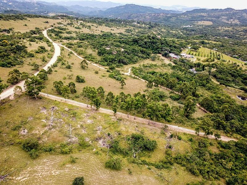 An aerial view of the small holding property showcasing the expansive landscape, natural vegetation, and gravel access roads leading to the main dwelling area.