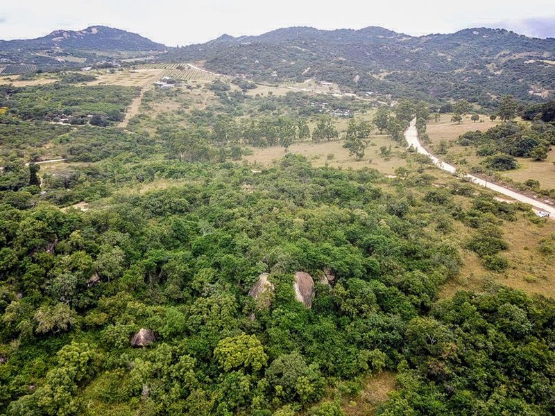 An aerial view of the expansive small holding property featuring natural indigenous vegetation, large rock formations, and a dirt access road through the landscape.