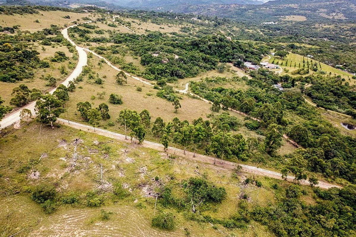 An aerial view of the small holding property showcasing the expansive landscape, natural vegetation, and gravel access roads leading to the main dwelling area.