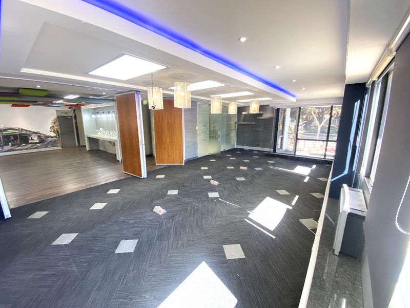 Spacious open-plan office area featuring modern recessed lighting, LED accent strips, carpeted flooring, and glass partitions, offering a bright and professional workspace.