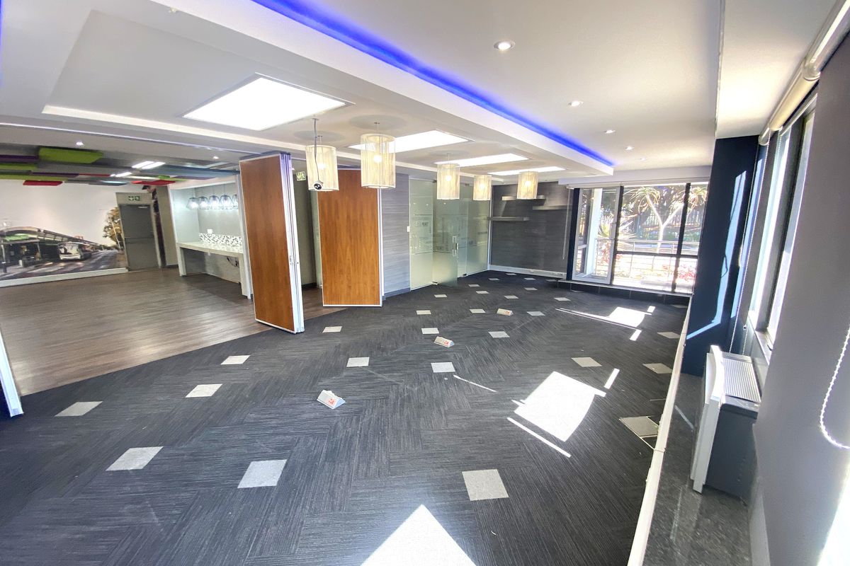 Spacious open-plan office area featuring modern recessed lighting, LED accent strips, carpeted flooring, and glass partitions, offering a bright and professional workspace.