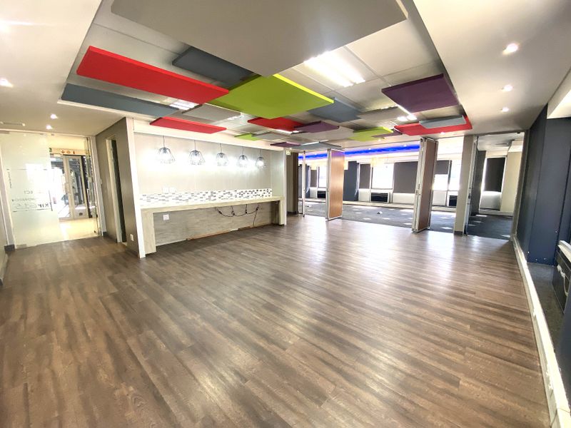Spacious open-plan office area featuring modern suspended acoustic ceiling panels, a built-in service counter, and flexible folding partition doors for versatile workspace configuration.