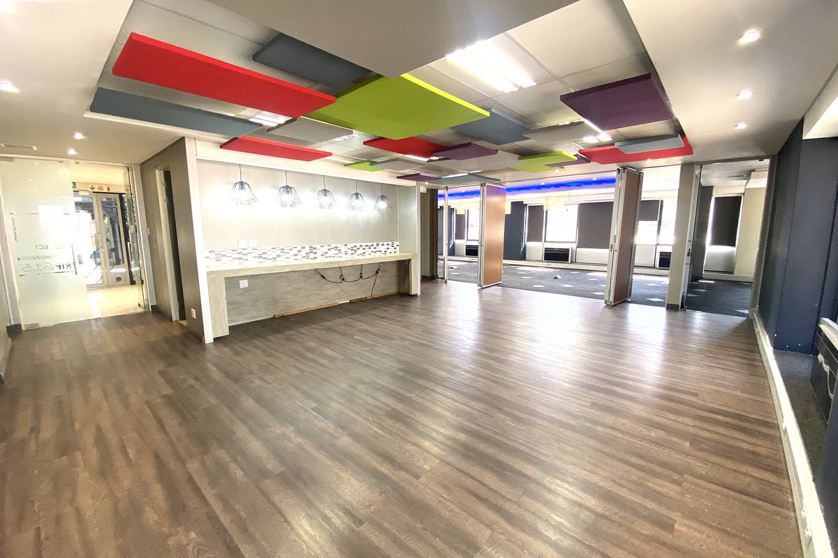 Spacious open-plan office area featuring modern suspended acoustic ceiling panels, a built-in service counter, and flexible folding partition doors for versatile workspace configuration.