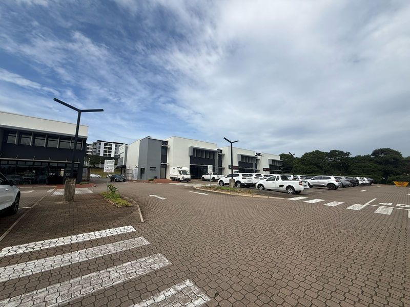 A well-maintained commercial retail property featuring a paved parking area, pedestrian access, and modern building facades.
