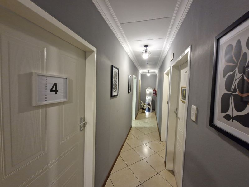 A well-maintained commercial hallway featuring tiled flooring, crown molding, and recessed ceiling lighting, providing access to multiple treatment rooms.
