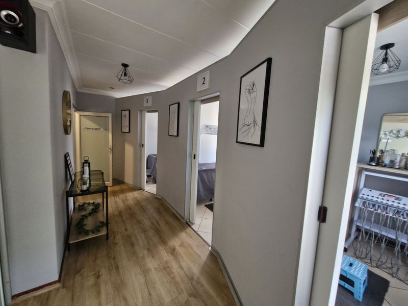 A well-maintained commercial hallway featuring laminate flooring, neutral wall finishes, and multiple access points to individual treatment or office rooms.