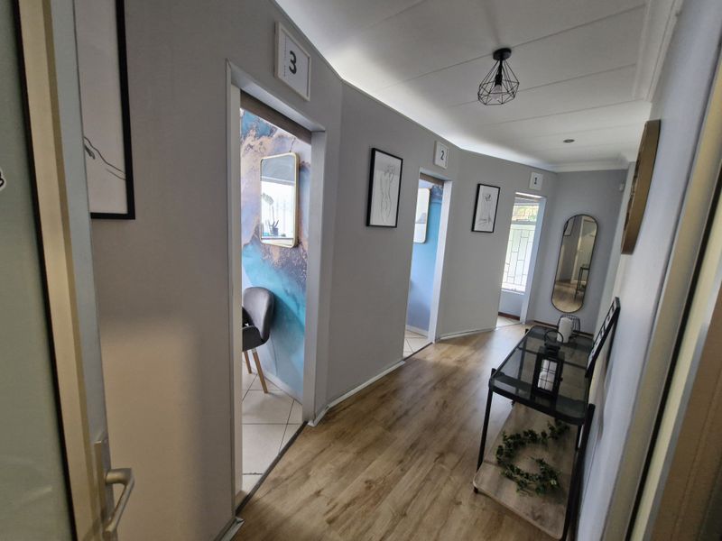 A well-lit commercial hallway featuring laminate flooring and numbered access points to individual rooms, providing a clean and professional circulation space.